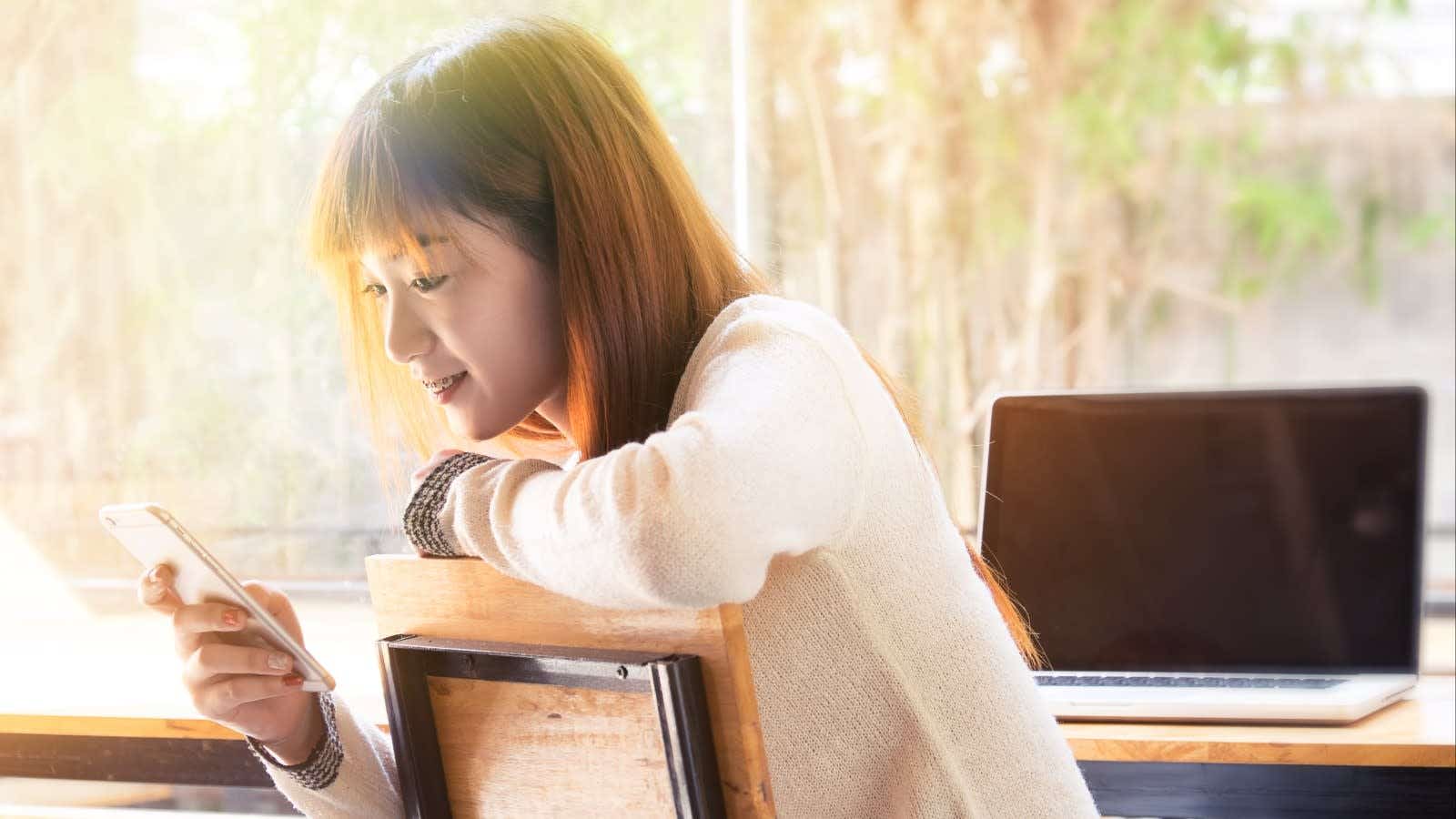 Woman using phone and laptop