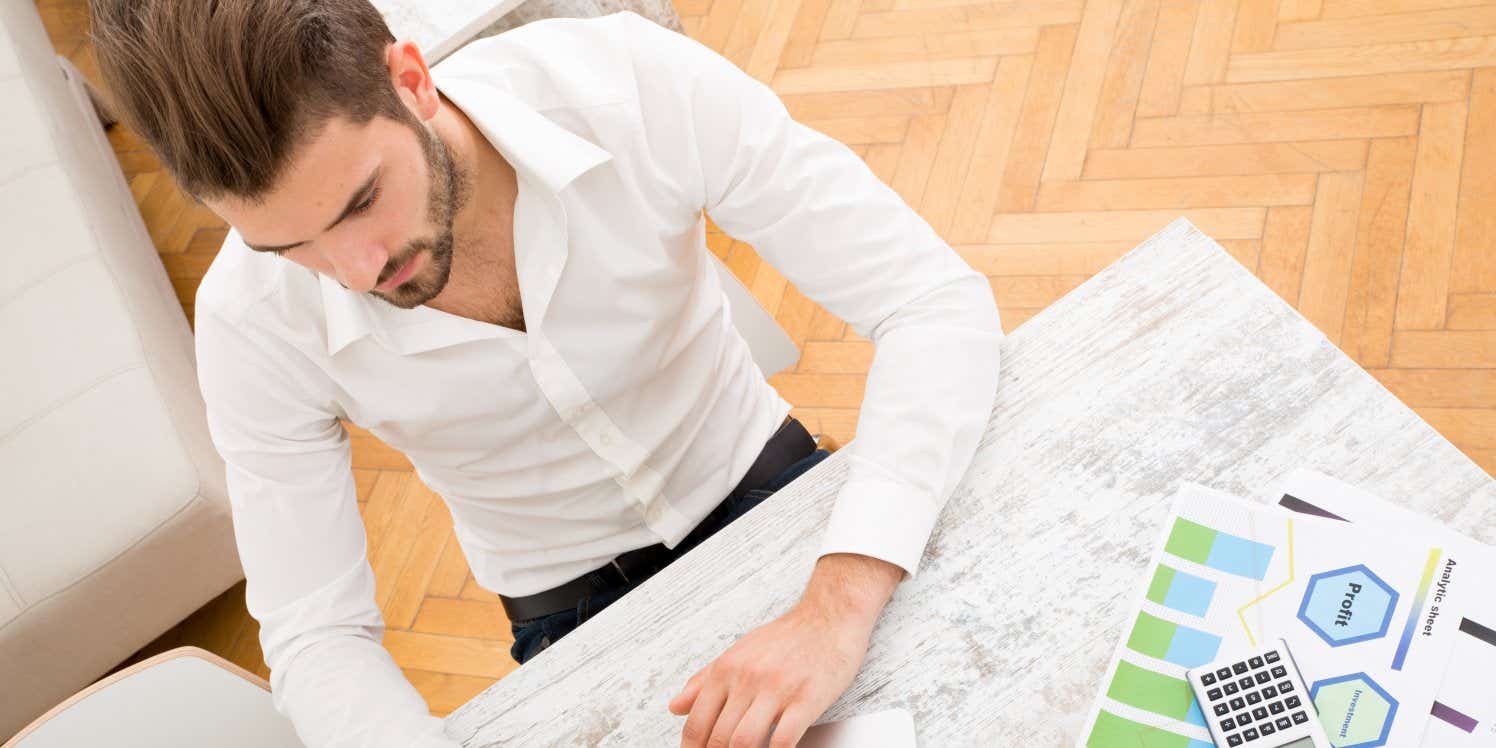 Man at desk working on laptop going over paperwork