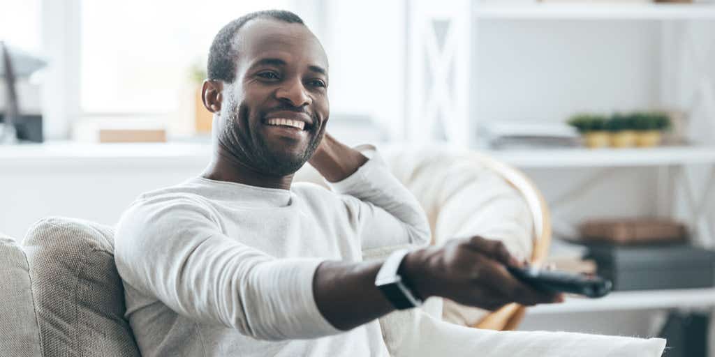 man watching TV with remote