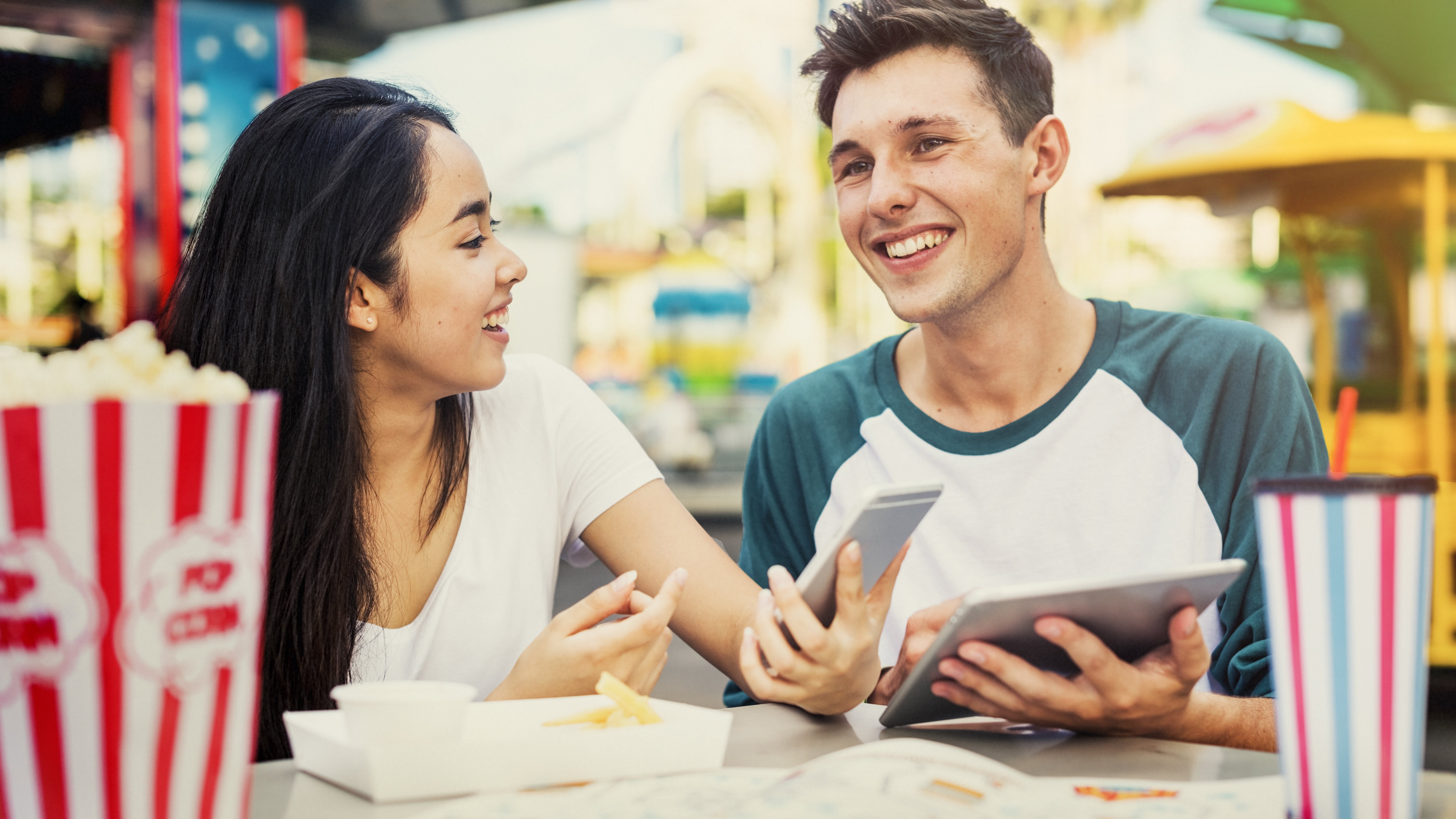 Happy young couple at a cafe with tablet and phone