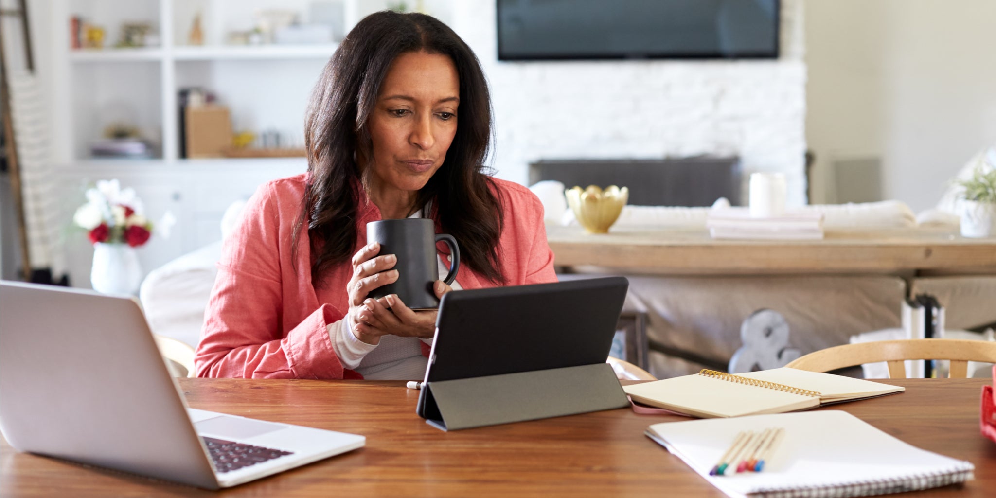 Woman working on tablet and laptop in her home