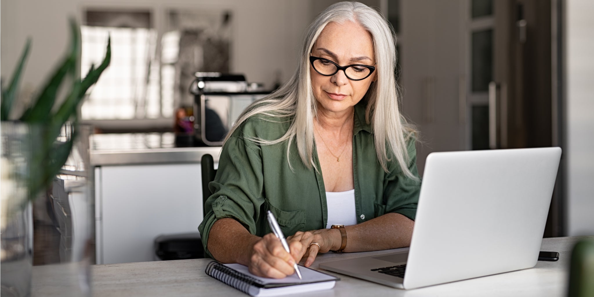 Lady making notes with laptop