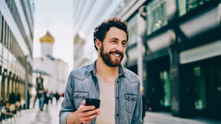 Man walking in the street holding his phone