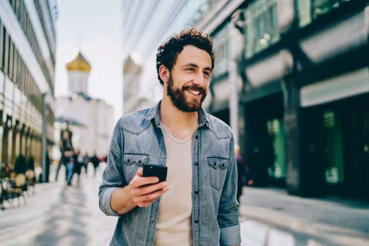 Man walking in the street holding his phone