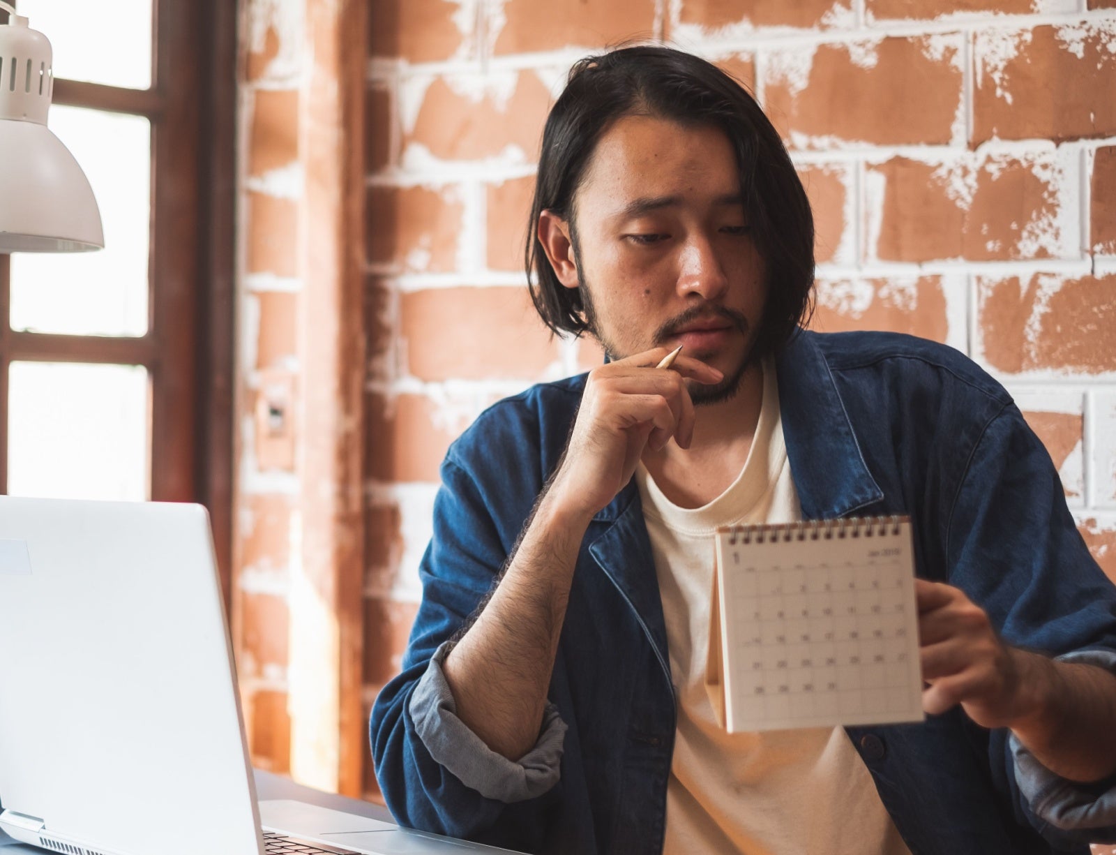 Man looks at a calendar while sitting at his desk