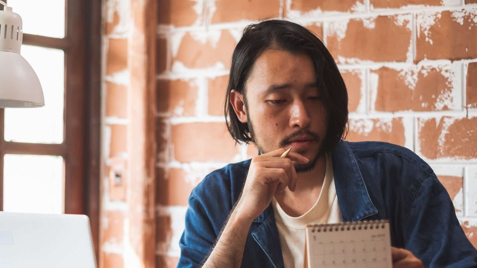 Man looks at a calendar while sitting at his desk