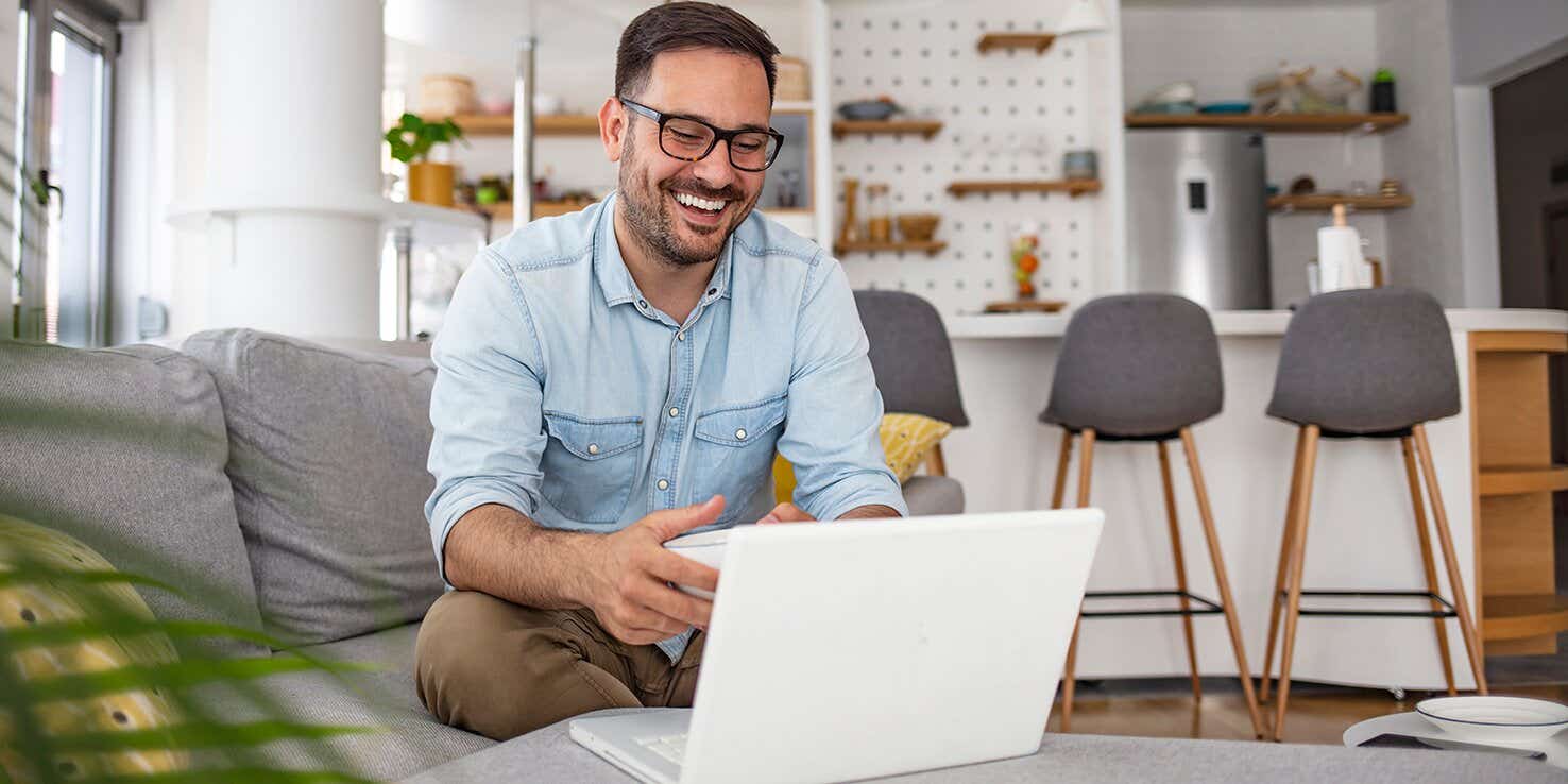 man laughing at his laptop at home