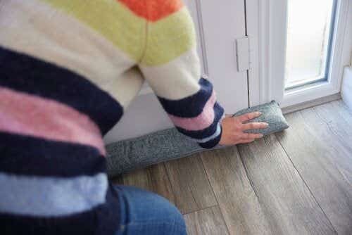 Woman draught-proofing a door