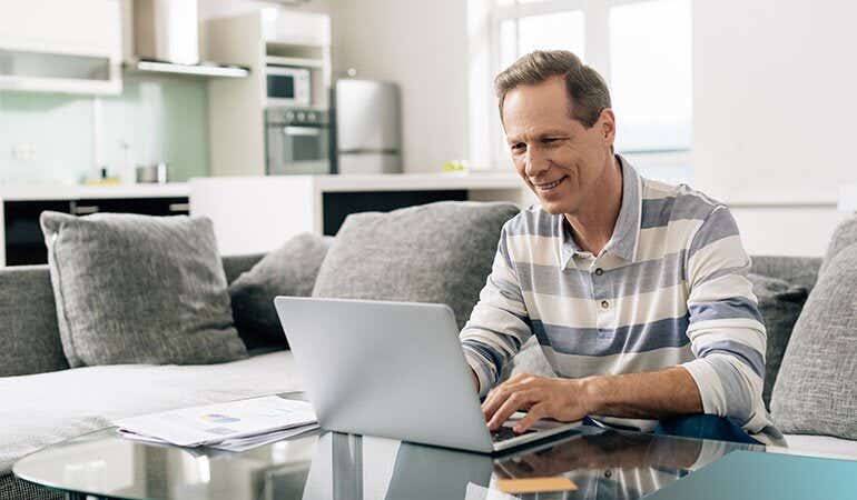 Man smiling on his laptop at home