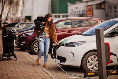 Woman charging EV with child