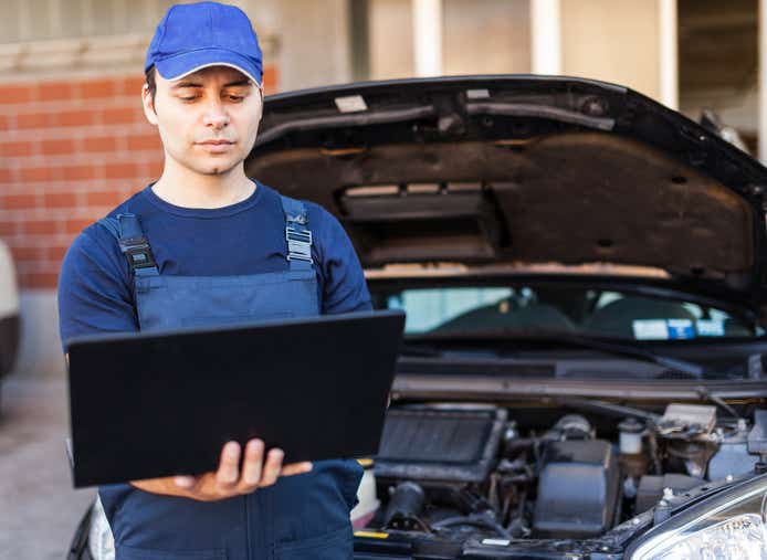 Professional mechanic using a laptop computer to check a car engine