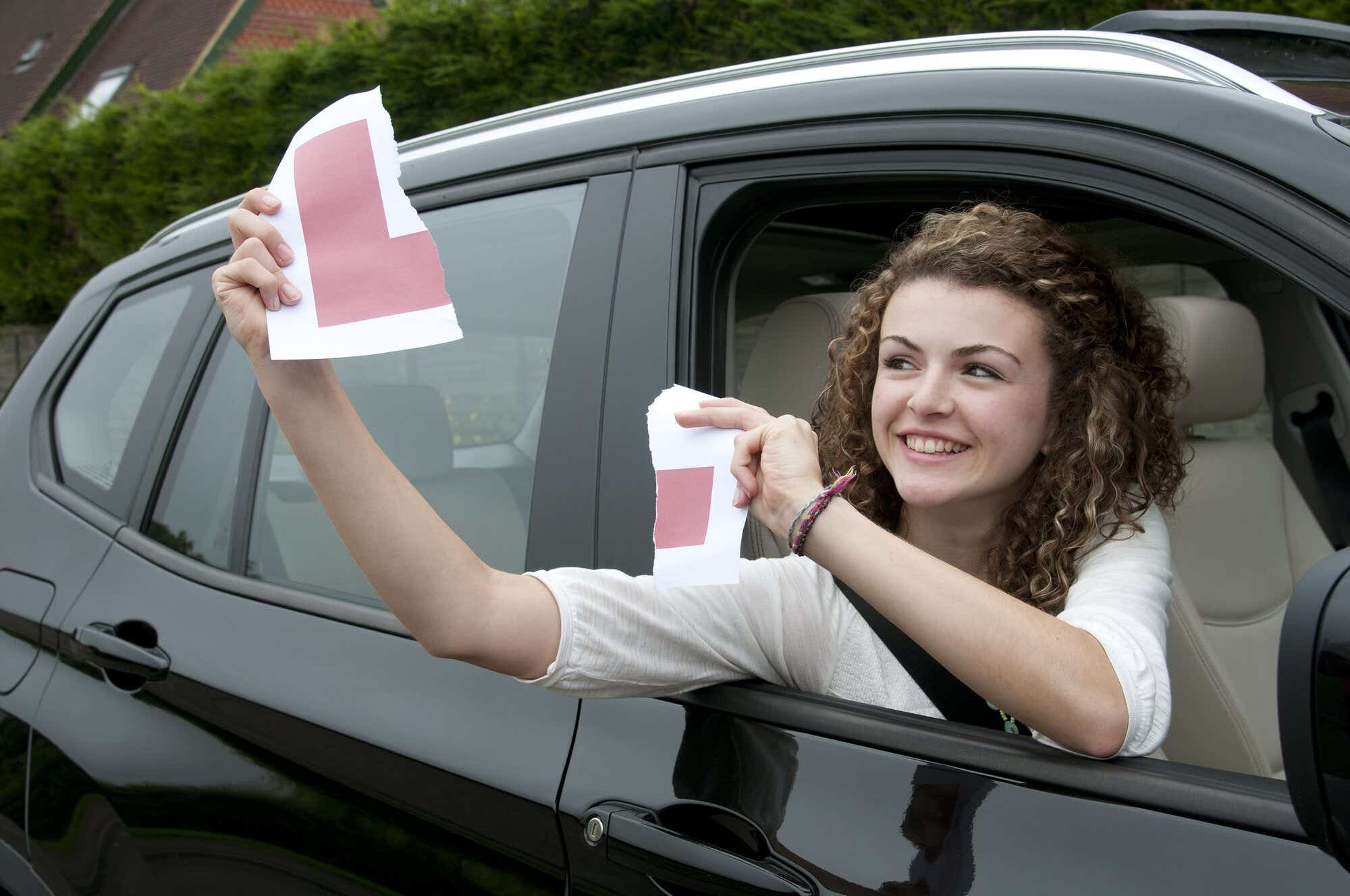 Young female driver holding L learner plate celebrating a pass rating 