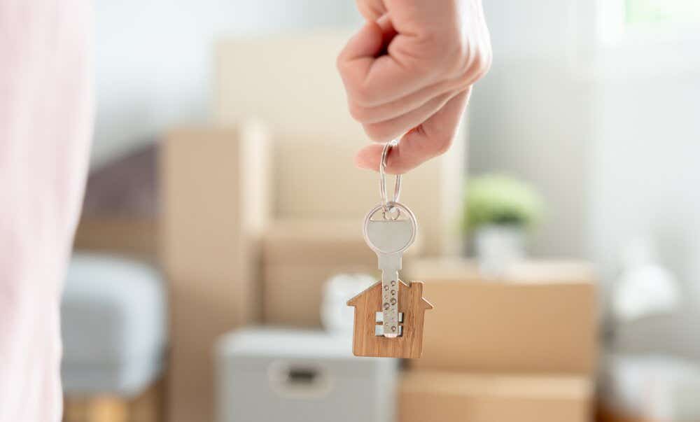 An image of someone holding house keys alongside packed boxes as they prepare to move house.