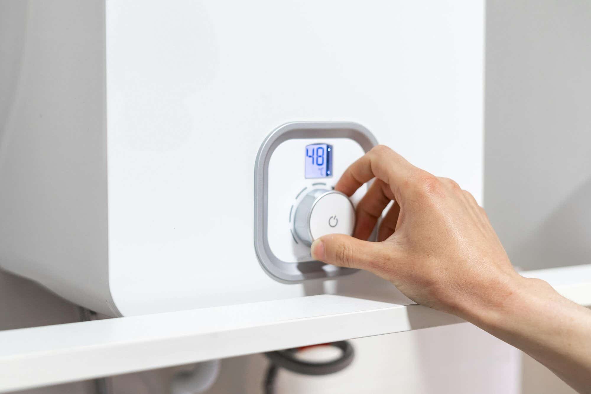 A person adjusting their boiler thermostat