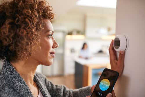 Woman using phone and turning down thermostat