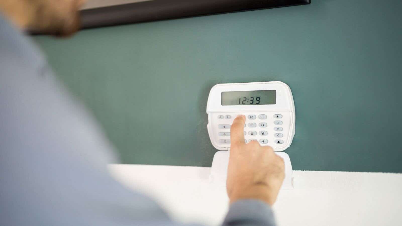 Persons hand pressing buttons on a burglar alarm