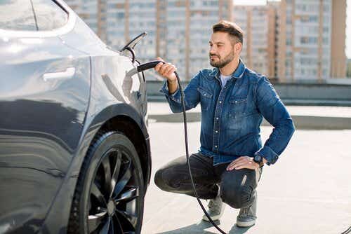 Man in denim shirt charging EV at public charging point