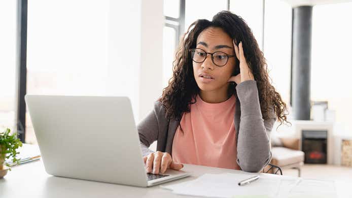 woman looking disappointed at her laptop sat at her desk at home