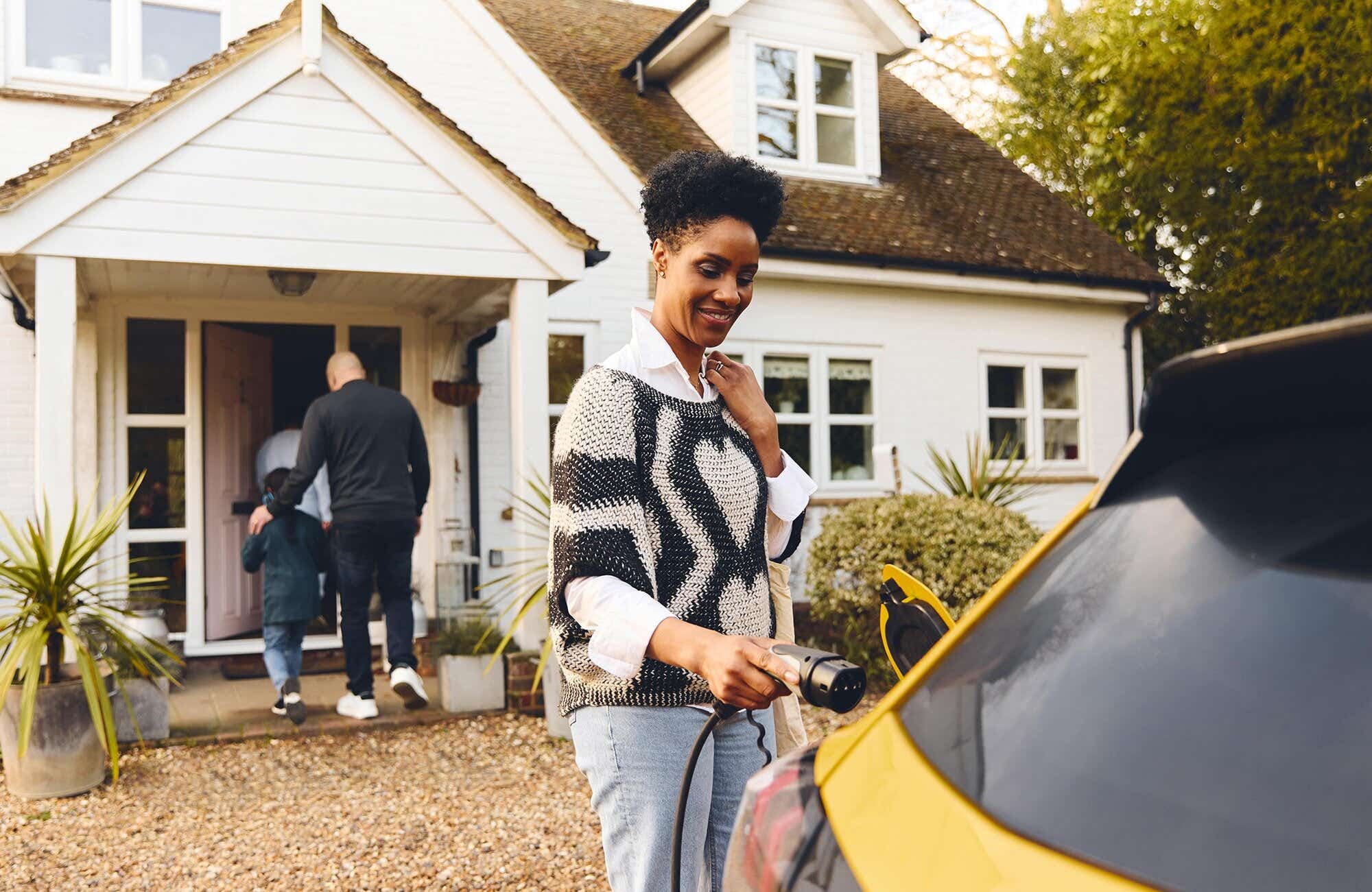 Woman charging her yellow car in front of her house