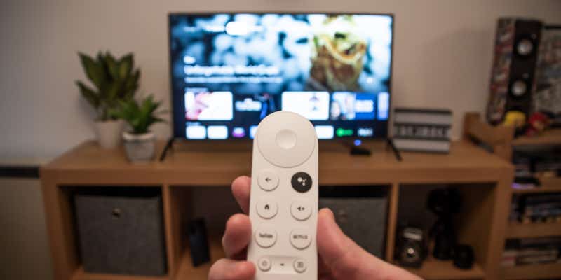 person holding a google chromecast remote in front of their tv