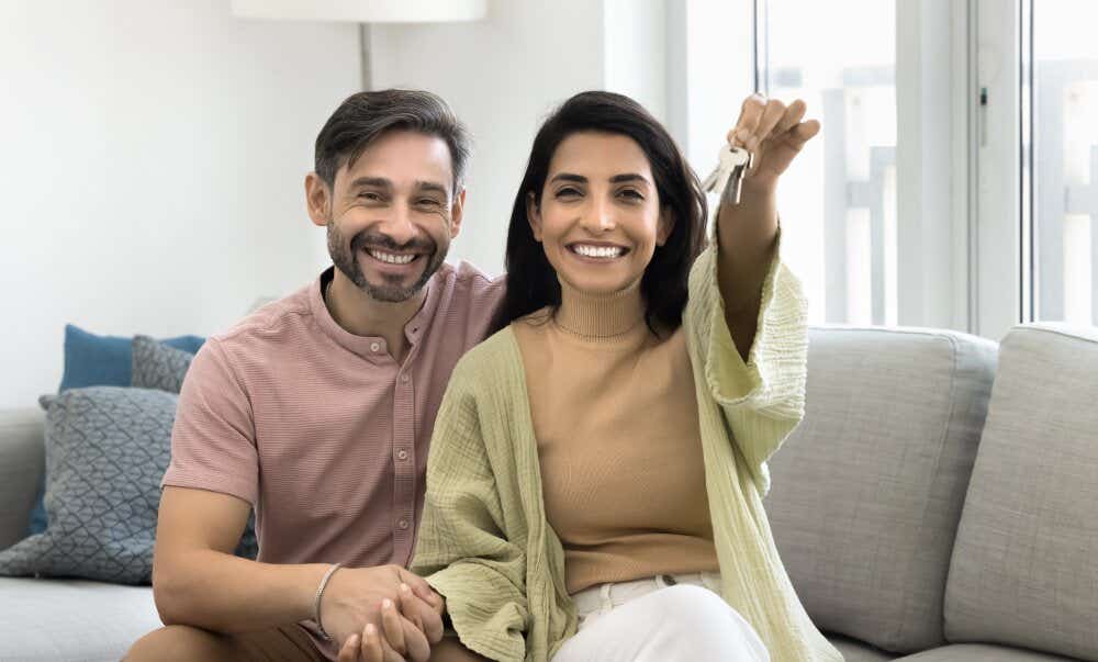 An image of a happy couple holding up new house keys after moving house.