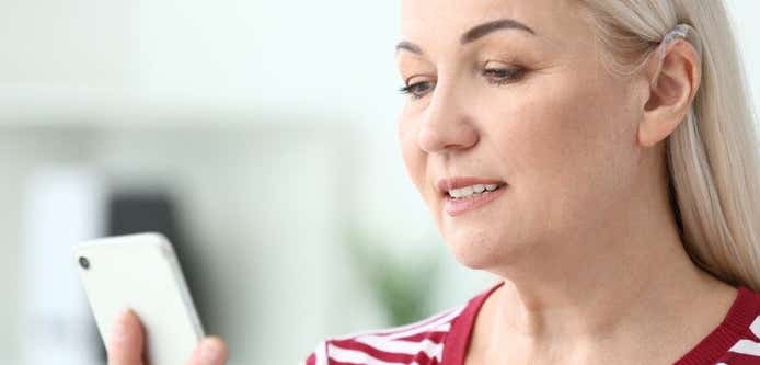 woman wearing a hearing aid using her smartphone