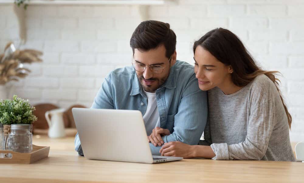 An image of a couple operating a laptop at home.