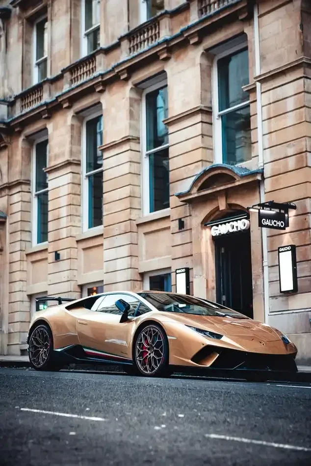 A gold performance sports car parked outside a building