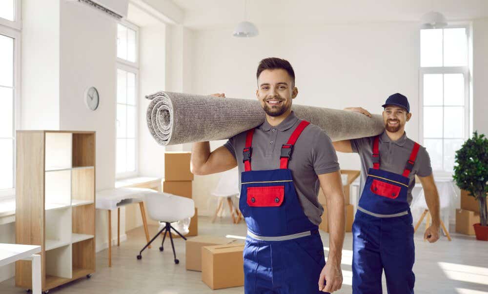 An image of two smiling removal men removing a carpet from a house during a home move.
