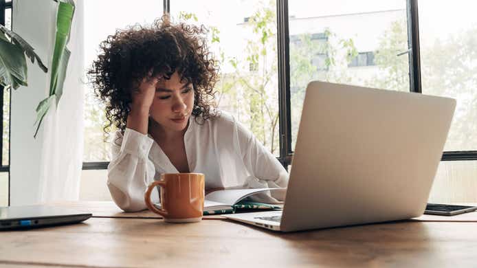 woman looking annoyed at her laptop complaining about her broadband provider