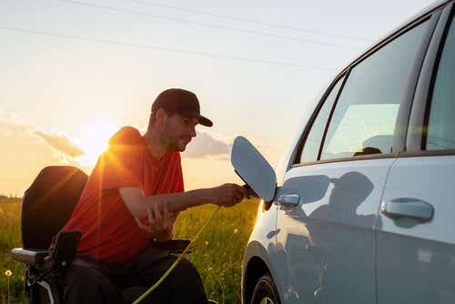 Man in wheelchair plugging electric car in