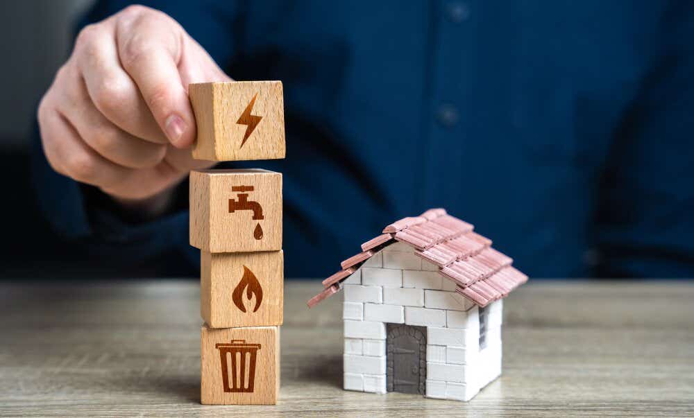 An image of a model home alongside four wooden squares with images representing different household services and utilities.