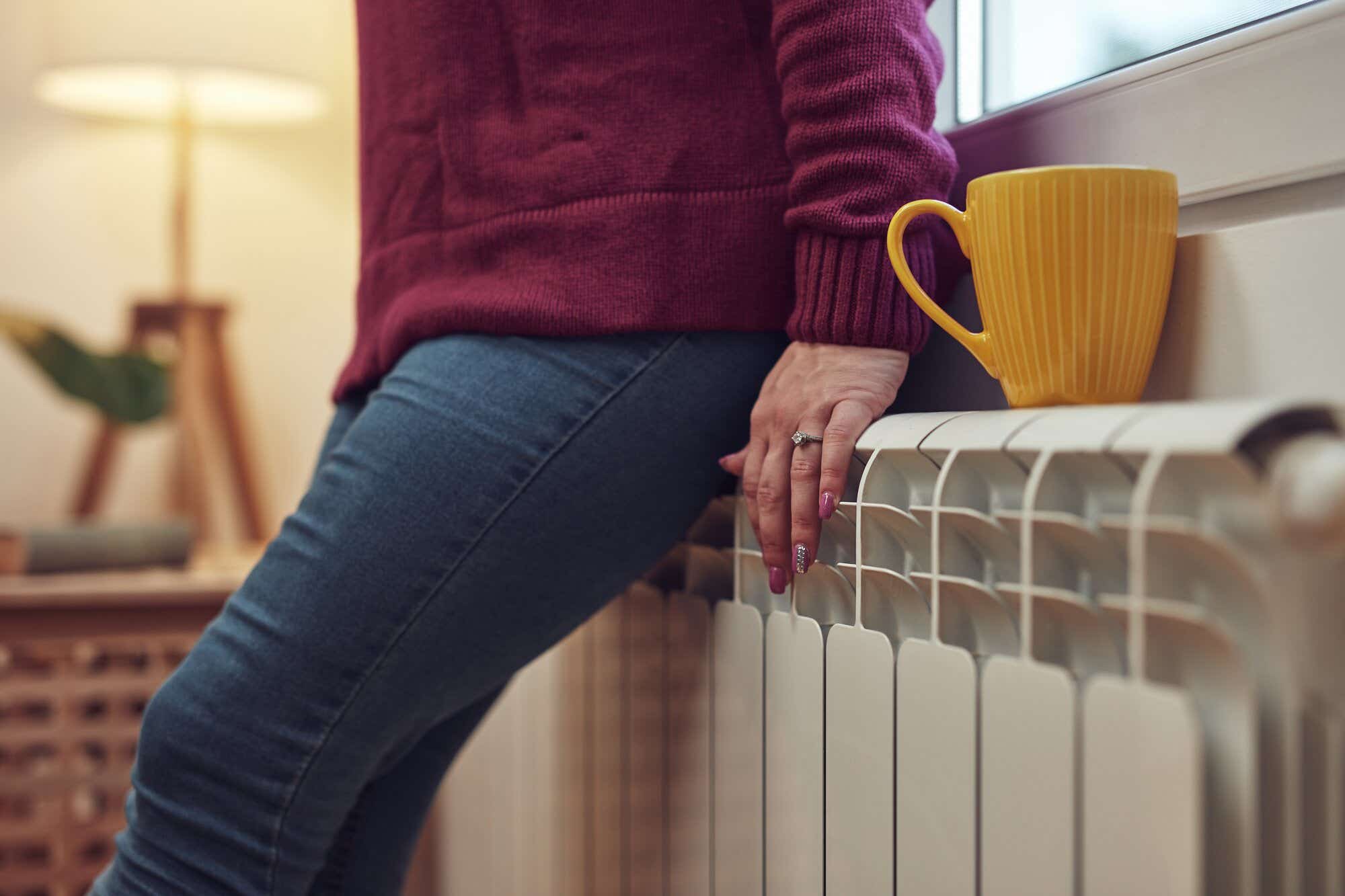 woman sitting on radiator with cup of tea