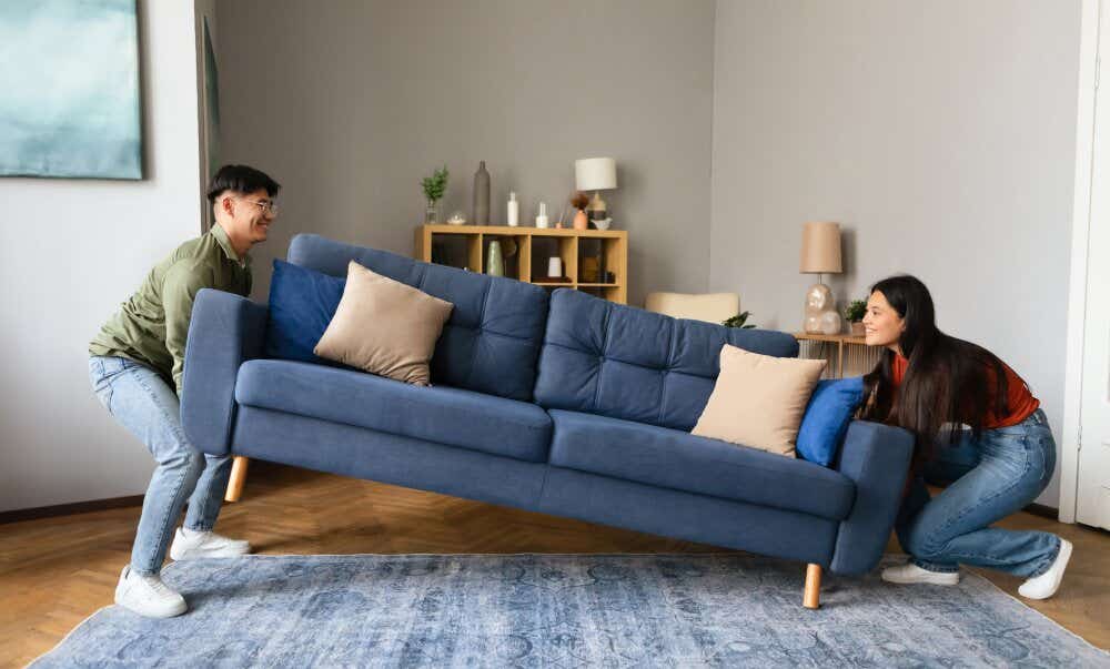 An image of a couple lifting a sofa in preparation for moving house.