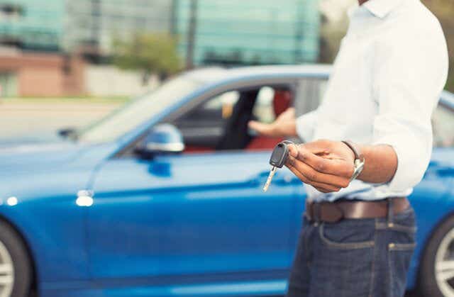 Man holding car keys in front of his car.