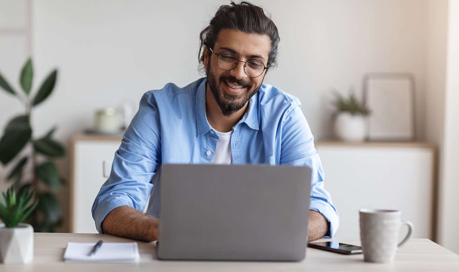 man smiling at his laptop while switching broadband