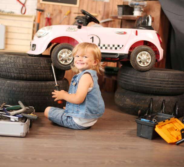 Child smiling next to car tyres