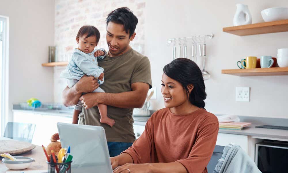 An image of a couple with their young child researching together at home on a laptop.