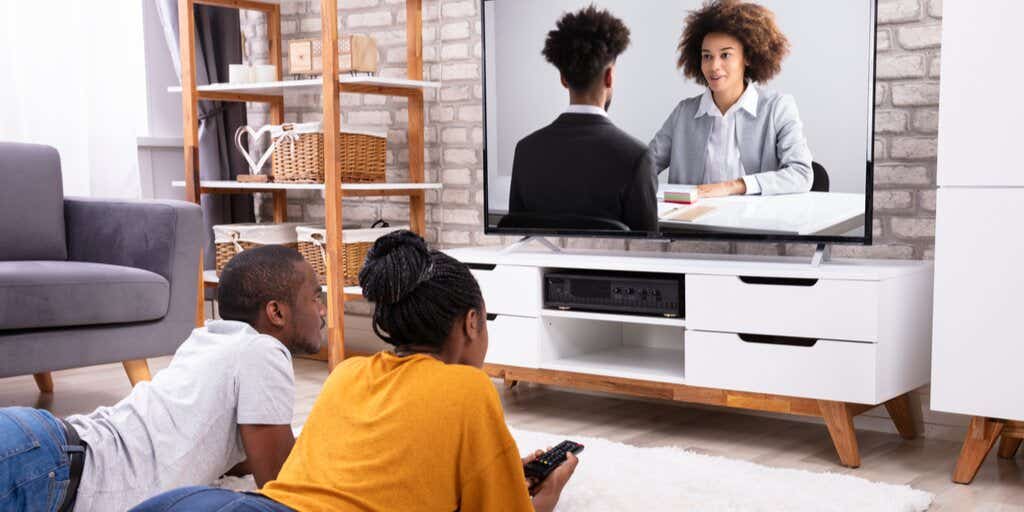 two people lying on their living room floor watching tv