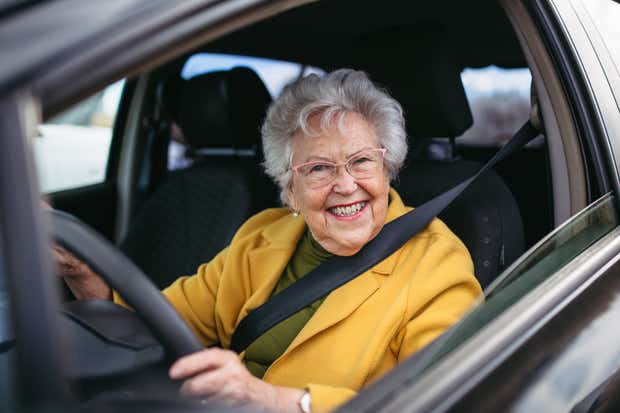 Smiling elderly woman driving a car