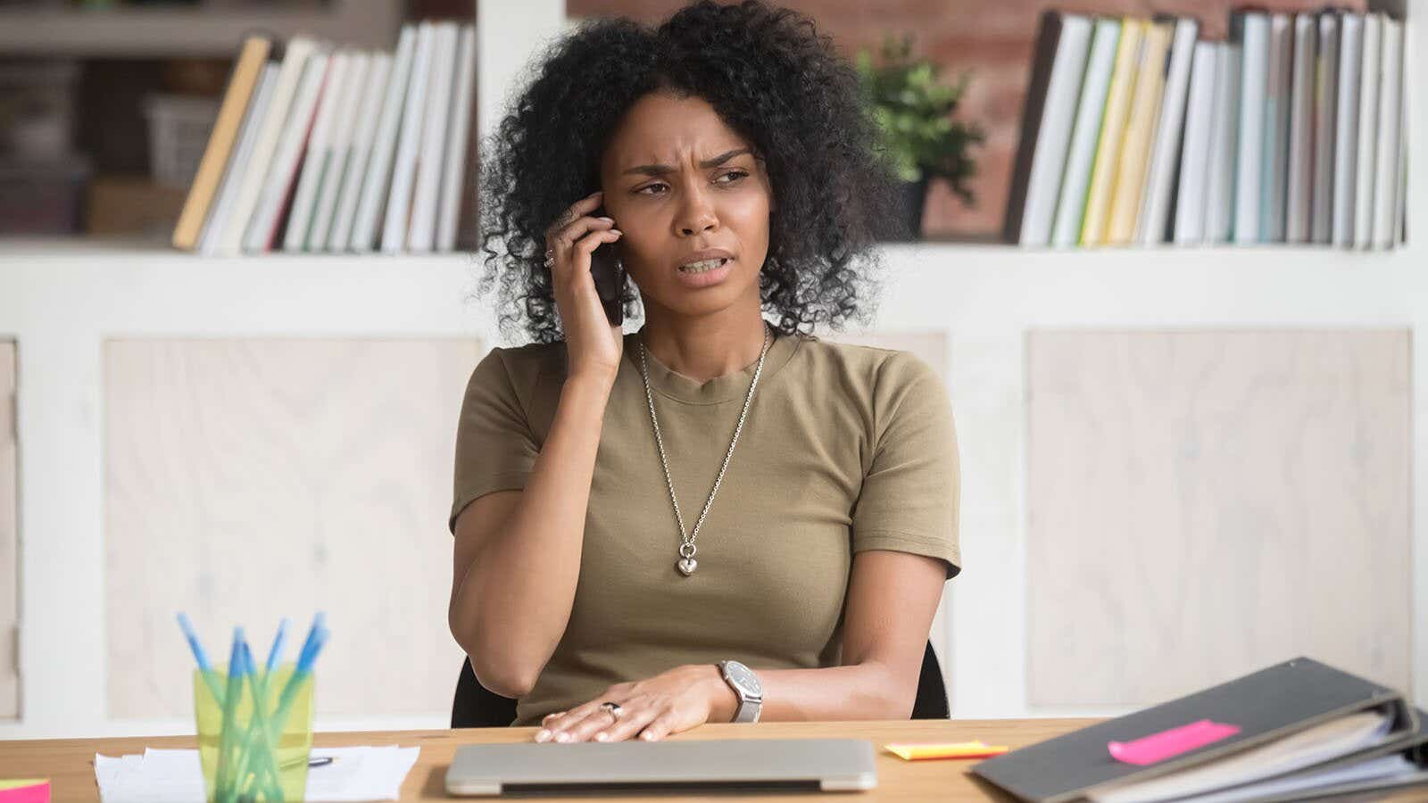 woman sat at her desk talking on the phone