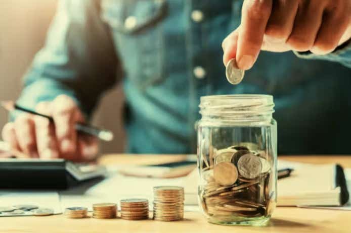 Man putting coins in jar