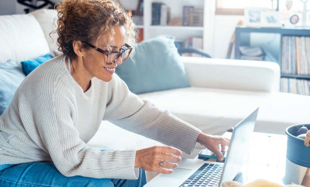 An image of a smiling woman using a laptop at home.
