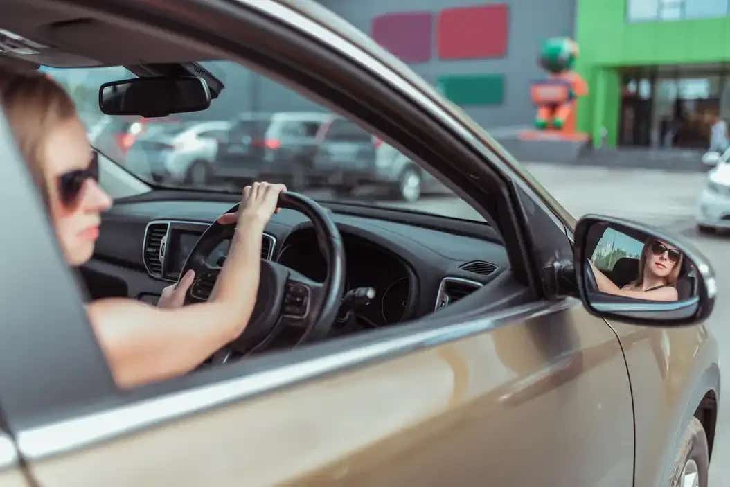 Woman driving a car and looking out her wing mirror