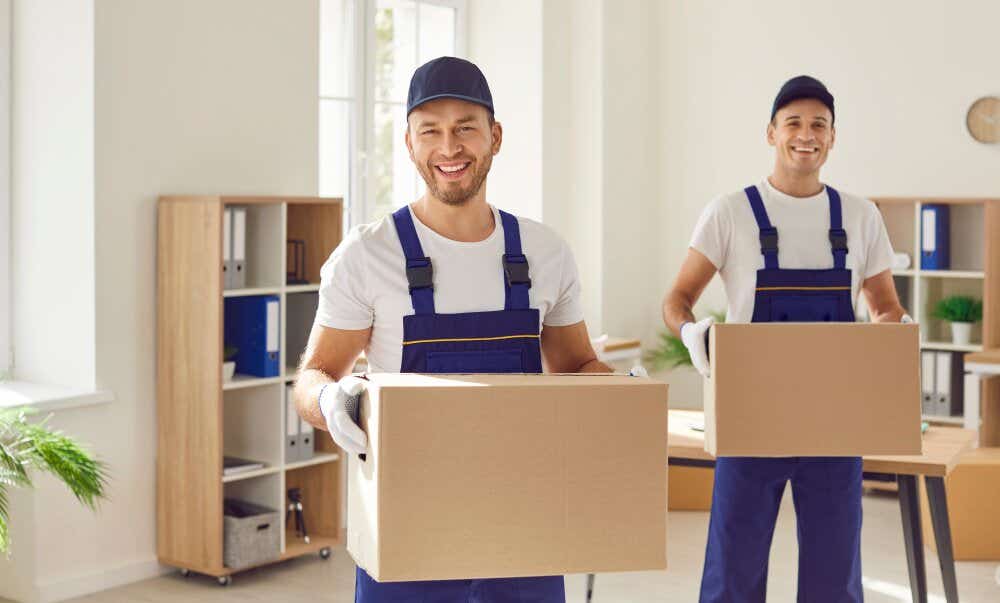 An image of two smiling removal men carrying boxes out of a house.