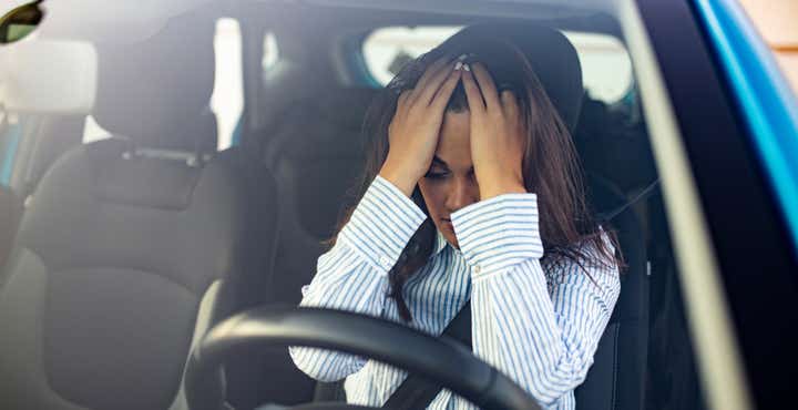 Women sat in the car with her hands on her head, demonstrating that she is stressed and anxious