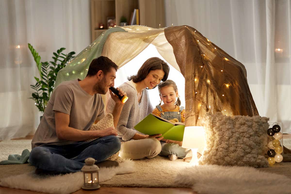 Family of three in homemade tent with fairy lights