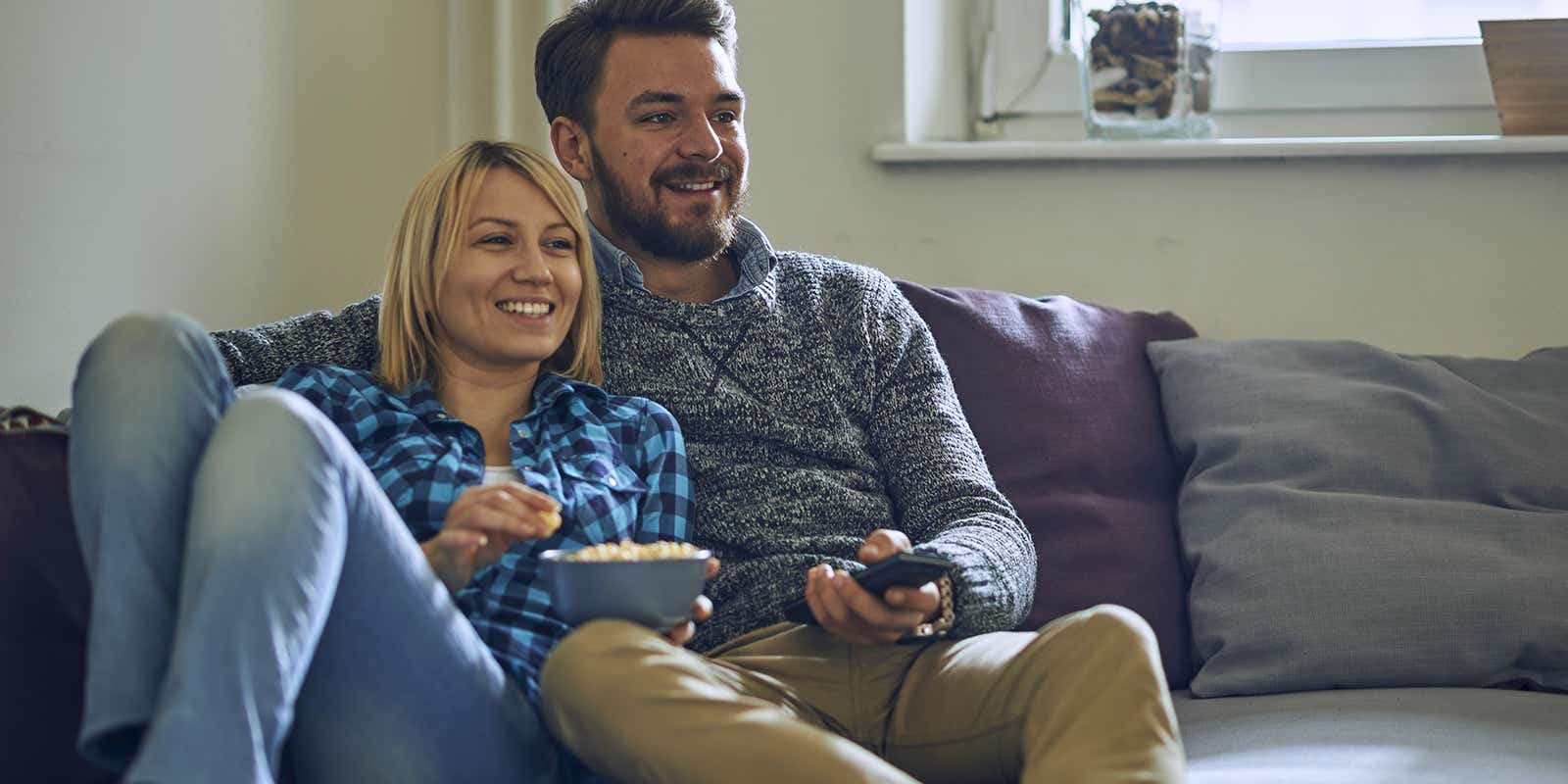 happy couple sat on the sofa watching a show on their wireless smart tv