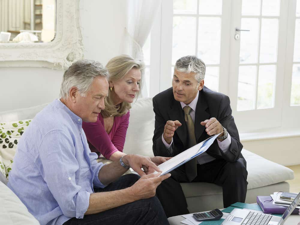 Help your kids on the property ladder – guarantor mortgages and more. Image of older couple discussing becoming mortgage guarantors with mortgage advisor