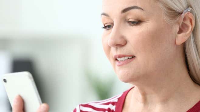 woman wearing a hearing aid using her smartphone
